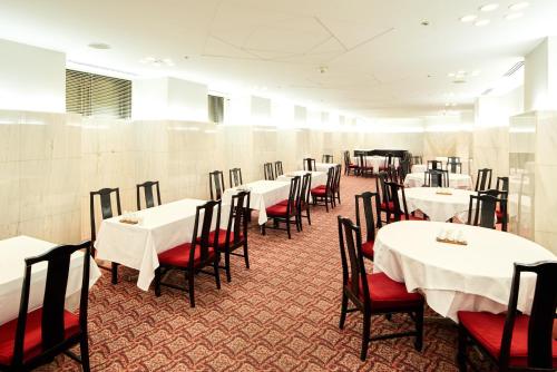 un comedor con mesas blancas y sillas rojas en Marroad Inn Hachioji, en Hachioji
