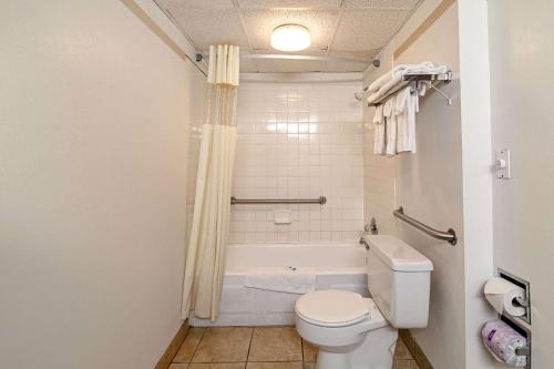 a bathroom with a toilet and a tub and a sink at Devils Lake Inn By OYO Near Devils Lake Regional Airport in Devils Lake