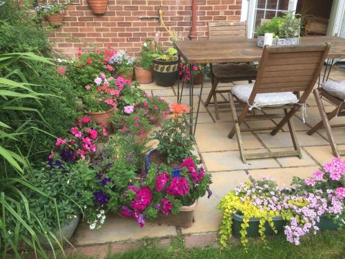 a patio with colorful flowers and a table and chairs at Clinton's Green B&B in Bracknell