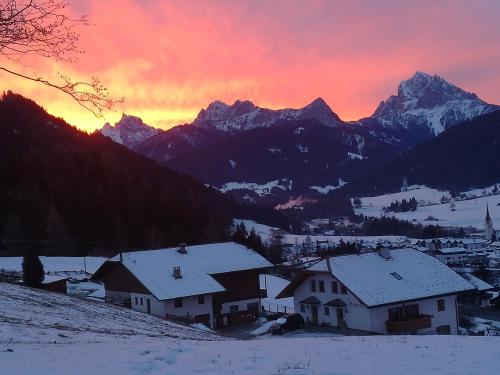 a group of houses in the snow at sunset at Stegerhof in Monguelfo