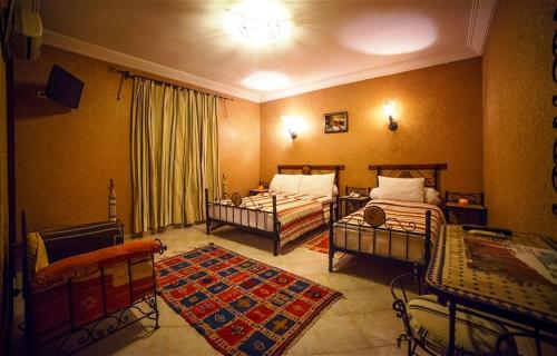 a bedroom with two beds and a rug at Hotel Salama STE SAL- AMA SUD SARL AU in Tafraoute