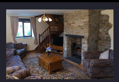 a living room with a stone fireplace and a blue couch at Hayloft Cottage in Merton