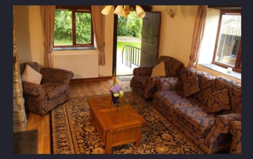 a living room with two couches and a coffee table at Hayloft Cottage in Merton