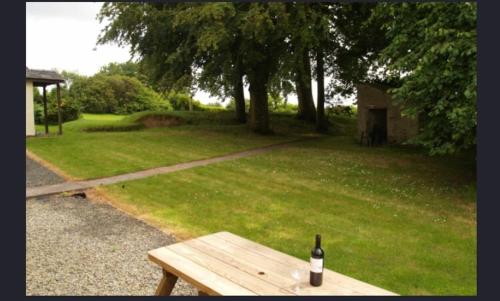 MertonにあるHayloft Cottageの木製のベンチに座るワイン1本