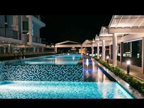 a large swimming pool with blue water at night at The Octagon Ipoh - Home Stay in Ipoh