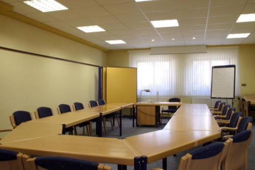 einen Konferenzraum mit Tischen, Stühlen und einem Whiteboard in der Unterkunft Spessarter Hof in Hobbach