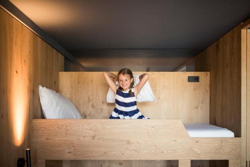 a little girl sitting on top of a bunk bed at Hotel Lamm in Castelrotto