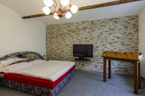 1 dormitorio con cama, mesa y TV en Penzion U Krotkých - Vyšší Brod en Vyšší Brod