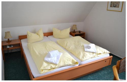 1 Schlafzimmer mit 2 Betten mit gelber Bettwäsche und Handtüchern in der Unterkunft Pension & Restaurant " Zum Harzer Jodlermeister" in Altenbrak