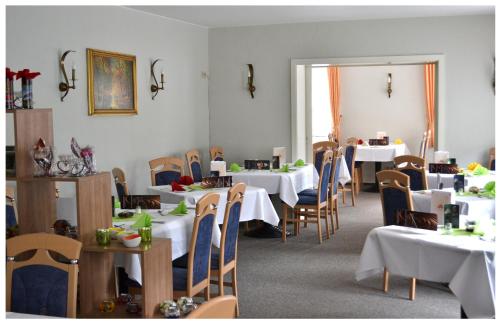 a dining room with white tables and chairs at Pension & Restaurant " Zum Harzer Jodlermeister" in Altenbrak