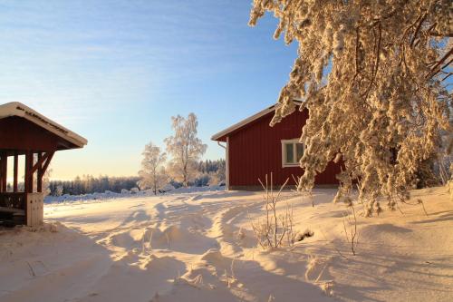 a red barn in the snow next to a building at Maatilamatkailu Jänisvaara in Kolinkylä