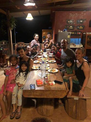 a group of people sitting around a wooden table at Bee Bee's Chalets home stay and trekking in Banlung