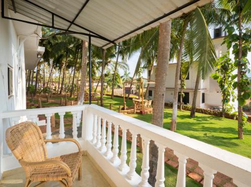 a balcony of a house with a chair and palm trees at de LAVENDER ac HOSTEL in Agonda