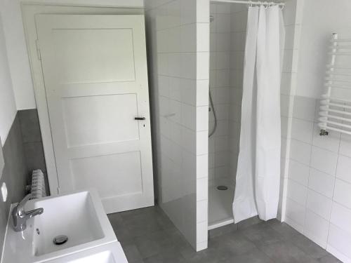a white bathroom with a shower and a sink at das weisse Haus am Fluss in Hahnenkopf