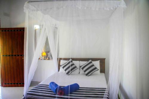 a bedroom with a canopy bed with blue shoes on it at Nice View Lodge in Sigiriya