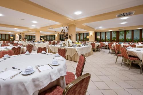 a banquet hall with tables and chairs with white tablecloths at Dioscuri Bay Palace in San Leone