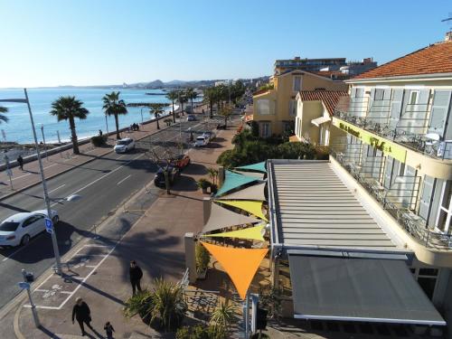 a view of a street with a building and the ocean at H&ocirc;tel du Bord de Mer "Le Vanill&eacute;" in Cagnes-sur-Mer