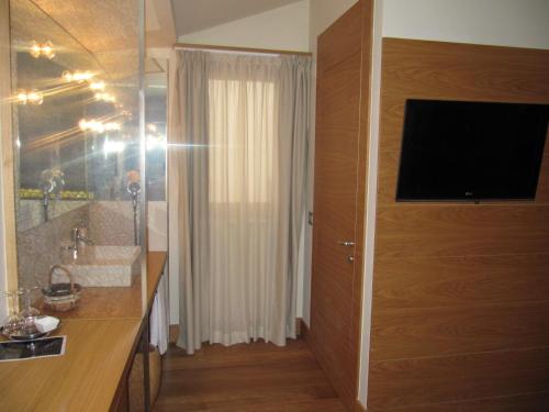 a bathroom with a shower and a television on a wall at Mario's Garni in Pescocostanzo