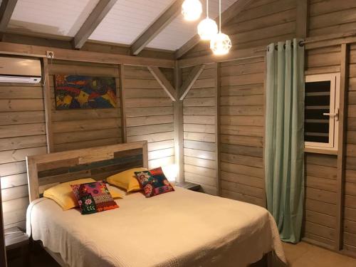a bedroom with a bed in a room with wooden walls at Charmant bungalow au cœur de l’île in Baie-Mahault