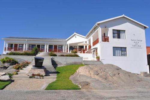 a large white house with a rock in front of it at Kairos Cottage B&B in Lüderitz