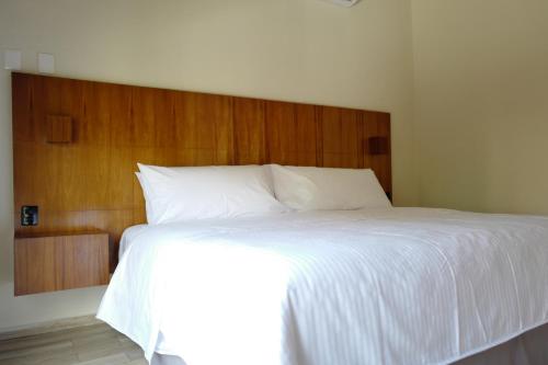 a bedroom with a large white bed with a wooden headboard at Villas La Ceiba in Playa del Carmen
