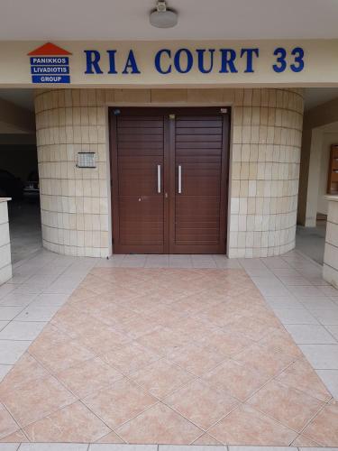a building with two brown doors and a ra court at Ria Court 33 in Larnaka