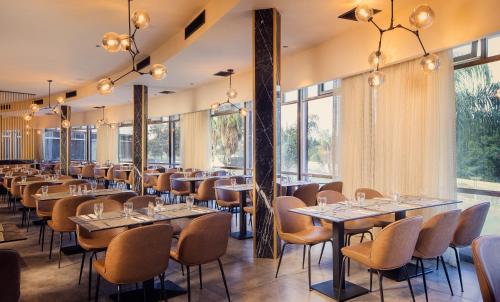 a restaurant with tables and chairs and large windows at Hotel Lake House Kinneret in Tiberias