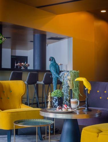 a table with a bird on it in a room with yellow chairs at Hotel Lake House Kinneret in Tiberias