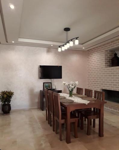 a dining room with a table and chairs and a television at Nouaceur Garden Comfort and Serenity Casa Airport in Nouaseur