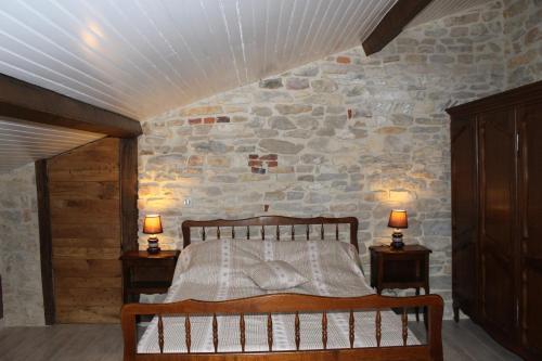a bedroom with a bed and two night stands with lamps at GITES LES MAISONS ROUGES in Jasseron