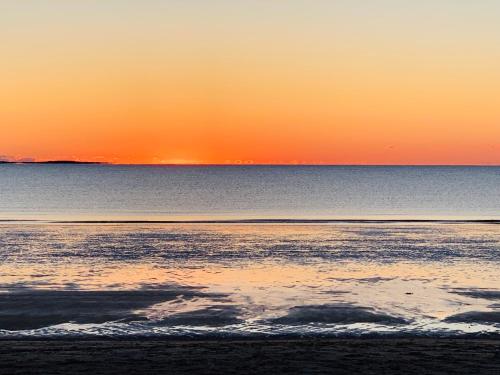 a sunset on the beach with the water at Alouette Beach Resort Economy Rooms in Old Orchard Beach