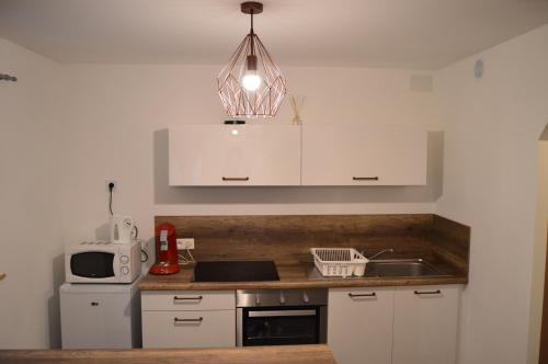 uma cozinha com armários brancos, um lavatório e um micro-ondas em Appartement le 972 gîte 3 étoiles em Riquewihr