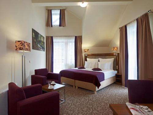 クリニツァ・ズドルイにあるHotel Mercure Krynica Zdrój Resort&Spaのベッド1台と椅子2脚が備わるホテルルームです。