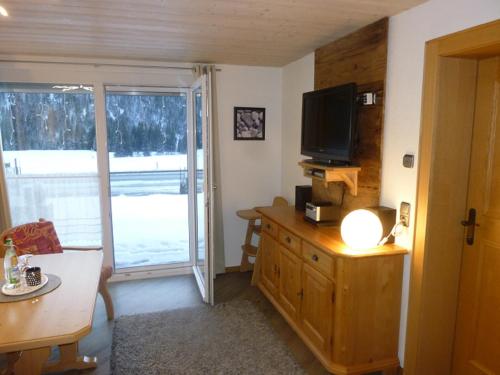 sala de estar con TV y tocador de madera con mesa en Ferienhof "Alpe Berg", en Balderschwang