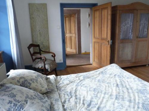 マンステールにあるGîte "Cadichon"のベッドルーム1室(ベッド1台、椅子1脚、ドア付)