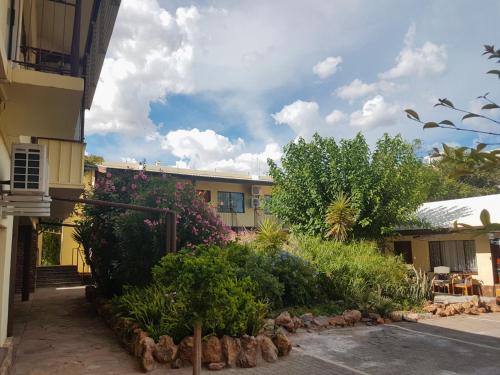 a building with bushes and plants in front of a building at Hotel Pension Steiner in Windhoek