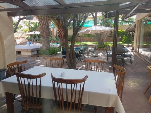 a table and chairs in a restaurant with a pool at Hotel Pension Steiner in Windhoek