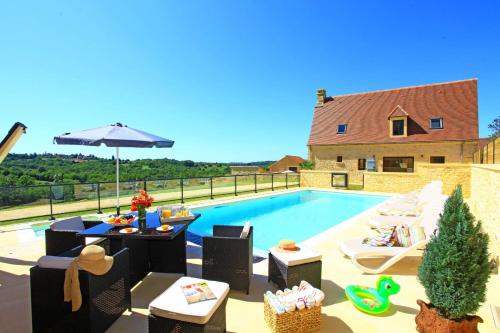 - une piscine avec des chaises, une table et un parasol dans l'établissement La Malonie, à Sarlat-la-Canéda
