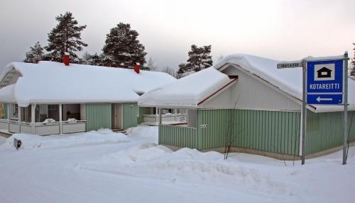 a green and white building with snow on the roof at Kotareitti Apartments in Rovaniemi