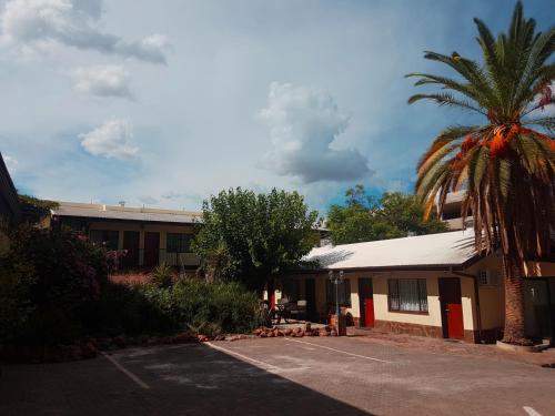 a building with a palm tree in front of it at Hotel Pension Steiner in Windhoek