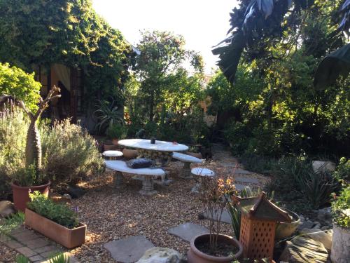 a patio with a table and benches in a garden at The Buddha Garden in Cape Town