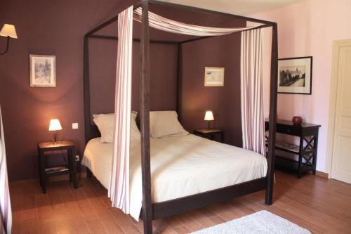 a bedroom with a four poster bed with white sheets at Chambres d'hôtes La Verrerie du Gast in Tanville