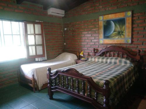 1 dormitorio con 2 camas y pared de ladrillo en ALOJAMIENTO VALLE DE SALTA en Salta