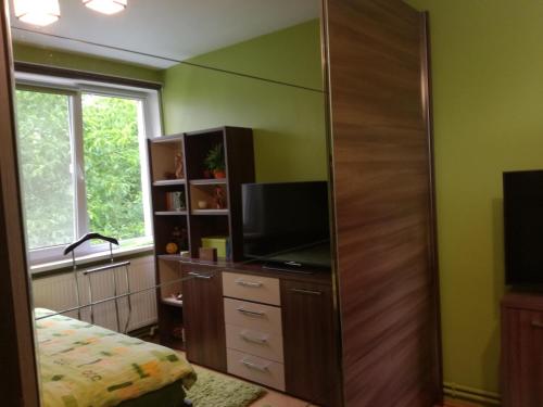 a bedroom with a dresser with a tv and a mirror at Green Apartment in Odorheiu Secuiesc