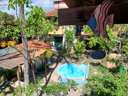 un patio trasero con piscina y un árbol en Pousada Hostal das Estrelas en Praia do Frances