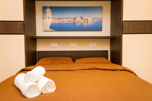 a bedroom with a bed with two towels on it at Lux Apartments in Xgħajra