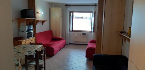 - un salon avec un canapé rouge et une fenêtre dans l'établissement Monolocale a Passo Tonale, à Passo del Tonale