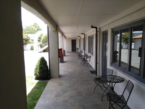 a hallway with chairs and tables on a building at Harvest Lodge Motel in Havelock North
