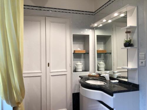 La salle de bains blanche est pourvue d'un lavabo et d'un miroir. dans l'établissement Château de Lannouan, à Landévant