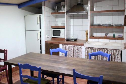 uma cozinha com uma mesa de madeira e cadeiras azuis em Casa Rural La Alfarera em Corral de Calatrava